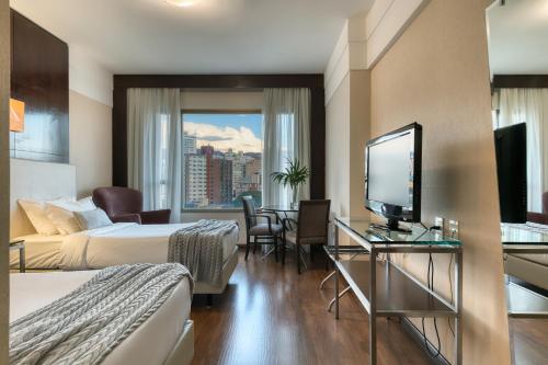a hotel room with two beds and a flat screen tv at Mercure Belo Horizonte Lourdes in Belo Horizonte