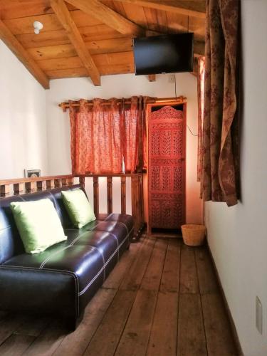 a living room with a leather couch and a television at Ganesha Hotel in San Cristóbal de Las Casas