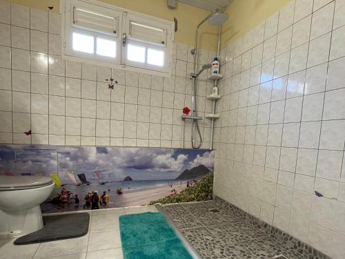 un bagno con un murale di una spiaggia sul muro di Colibri de la Pointe a Le Robert