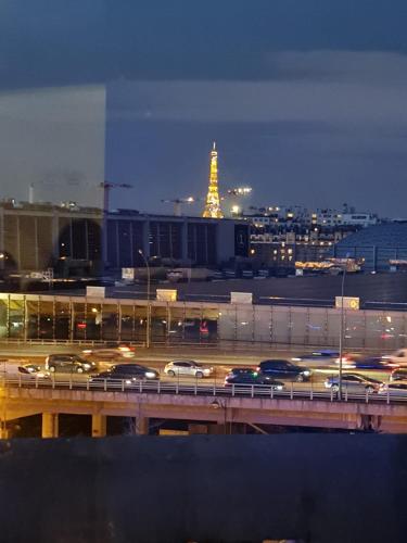 een stad met verkeer op een snelweg 's nachts bij APPARTEMENT AVEC VUE SUR LA TOUR EIIFEL in Issy-les-Moulineaux