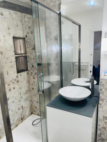 une salle de bain avec deux lavabos et une douche en verre dans l'établissement APPARTEMENT AVEC VUE SUR LA TOUR EIIFEL, à Issy-les-Moulineaux
