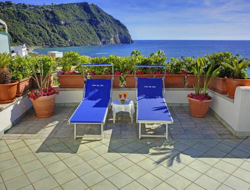 two blue chairs and a table on a balcony with the ocean at Appartamenti Casa del Sole in Ischia