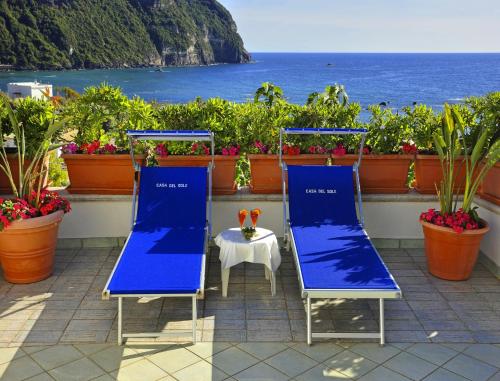 two blue chairs and a table on a balcony with the ocean at Appartamenti Casa del Sole in Ischia
