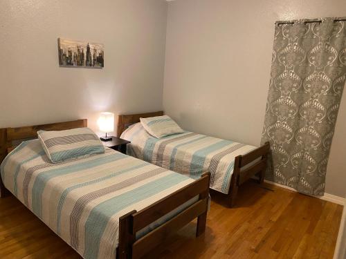 1 dormitorio con 2 camas y una lámpara en el suelo de madera en Cozy house with large free parking on premises, en Springfield