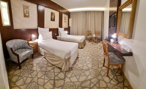Habitación de hotel con 2 camas y 2 sillas en Jiwar Al Madina Hotel en Medina
