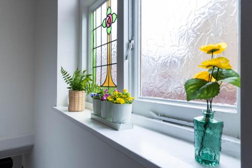 a window sill with flowers and a stained glass window at Beautiful 4 bedroom house with free parking Luton in Luton