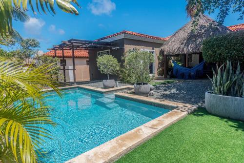 a swimming pool in front of a house at Lama y Solo Unique private room walking distance to the Beach in Palm-Eagle Beach