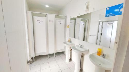 La salle de bains blanche est pourvue de deux lavabos et de miroirs. dans l'établissement Hostal Aires del Sur Centro de Rancagua, à Rancagua