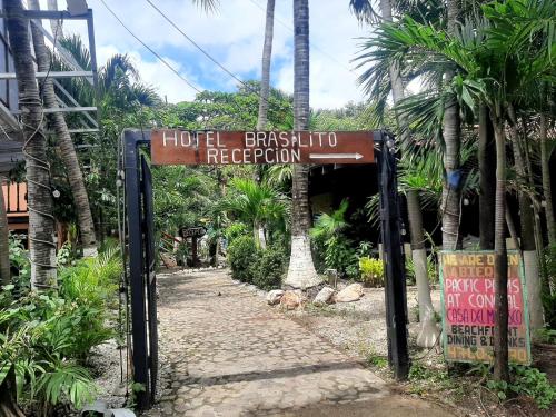 a sign for a hotel in a resort with palm trees at Hotel Brasilito in Brasilito