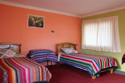 2 camas en una habitación con paredes de color naranja en LOVELAND AMANTANI LODGE - Un lugar encantado en Ocosuyo