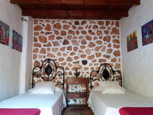 2 camas en una habitación con una pared de piedra en Casa antigua en el centro de Fuerteventura, en Antigua