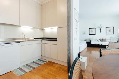 uma cozinha com armários brancos, uma mesa e uma sala de estar em La casa di Isa em Lecco