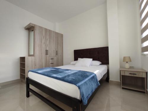 a bedroom with a bed with a blue blanket on it at APARTAMENTO PUERTO MADERA in Manta