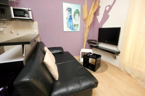 a living room with a black leather couch and a television at Apartments with WiFi Dubrovnik - 4681 in Dubrovnik