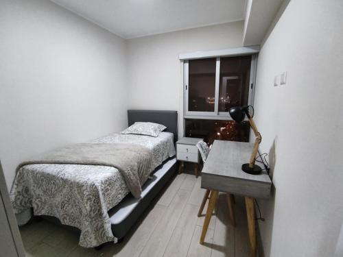1 dormitorio con cama, escritorio y ventana en Epiqe Manuel Olguin 600 en Lima