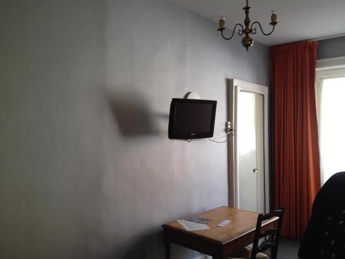 a room with a table and a tv on the wall at Hotel Du Nord in Besançon