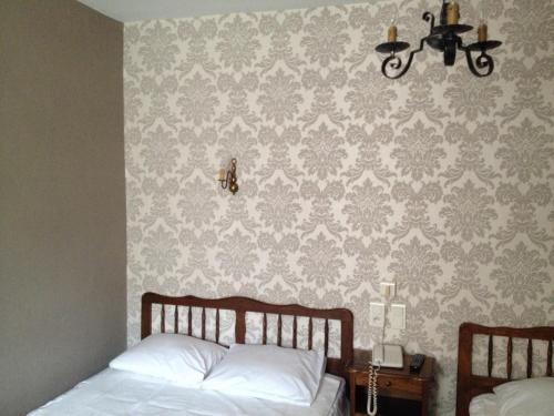 a bedroom with two beds and a wall with wallpaper at Hotel Du Nord in Besançon