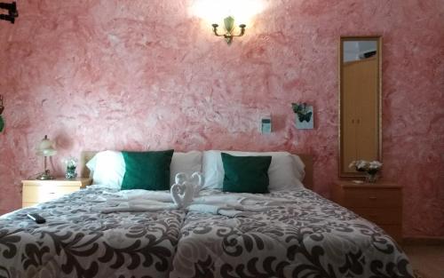 a bedroom with a large bed with a pink wall at Hostal El Patio in Alhaurín de la Torre