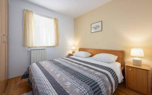 a bedroom with a bed with two pillows and a window at Family friendly apartments with a swimming pool Basanija, Umag - 3402 in Savudrija