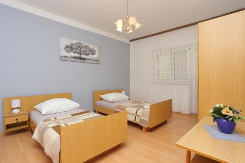 una camera con due letti e un tavolo con fiori di Apartments with a parking space Nemira, Omis - 4652 a Tice