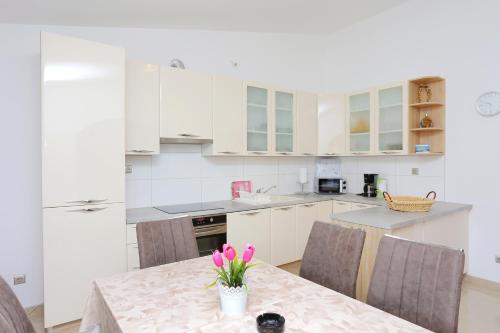 a kitchen with a table with pink flowers on it at Apartments with a parking space Nemira, Omis - 4652 in Tice