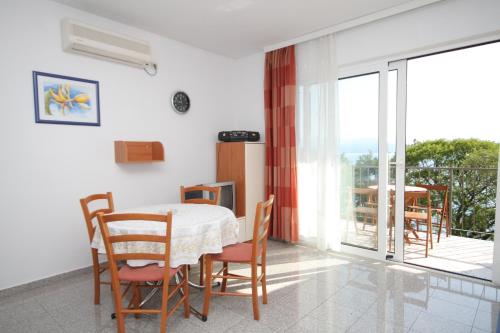 a dining room with a table and chairs and a balcony at Apartments by the sea Medveja, Opatija - 3430 in Medveja