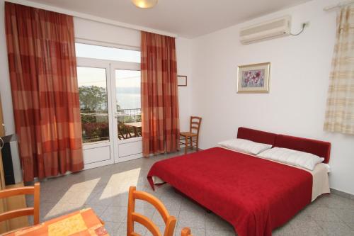 a bedroom with a red bed and a balcony at Apartments by the sea Medveja, Opatija - 3430 in Medveja