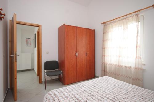 a bedroom with a bed and a cabinet and a chair at Apartment Nerezine 3451c in Nerezine