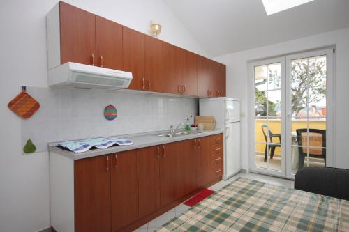 a kitchen with wooden cabinets and a white refrigerator at Apartment Nerezine 3451c in Nerezine