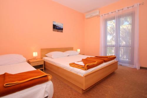 2 camas en una habitación con paredes de color naranja y ventana en Apartments and rooms with a swimming pool Cavtat, Dubrovnik - 4733, en Cavtat