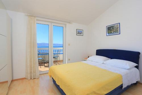 a bedroom with a large bed with a yellow blanket at Apartments by the sea Balica Rat, Omis - 2753 in Tice