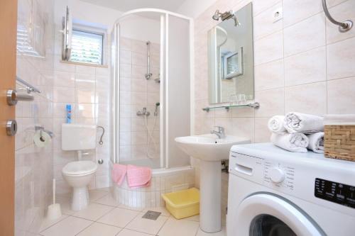 a bathroom with a toilet sink and a washing machine at Apartment Stanici 2764a in Tice