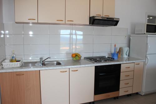 a kitchen with a sink and a stove and refrigerator at Apartments by the sea Mimice, Omis - 2774 in Mimice