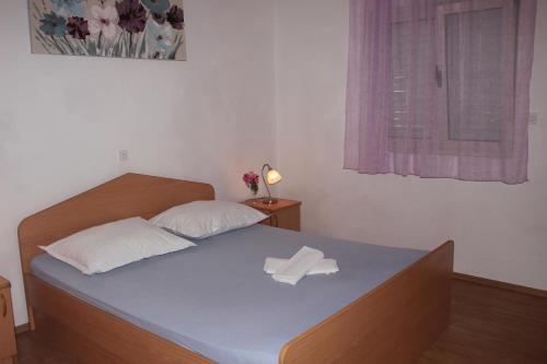 a bedroom with a bed with a pillow and a window at Apartments by the sea Mimice, Omis - 2774 in Mimice