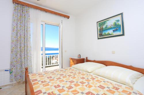 een slaapkamer met een bed en een groot raam bij Apartments with a parking space Stanici, Omis - 2818 in Tice