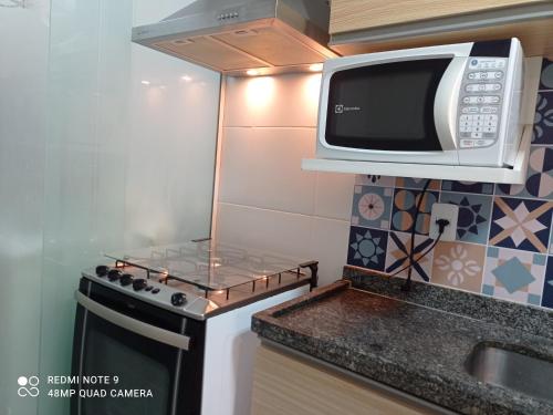 a microwave above a stove in a kitchen at Mata Atlântica - Excelente custo benefício na Praia do Morro in Guarapari