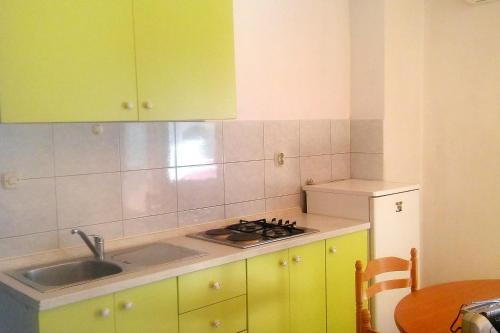 a kitchen with green cabinets and a sink and a table at Apartment Drvenik Donja vala 2732a in Drvenik