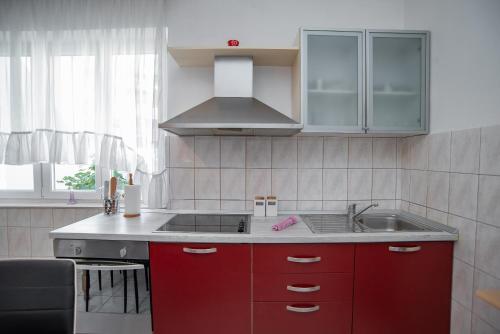 a kitchen with red cabinets and a sink at Apartments by the sea Sumpetar, Omis - 2808 in Sumpetar