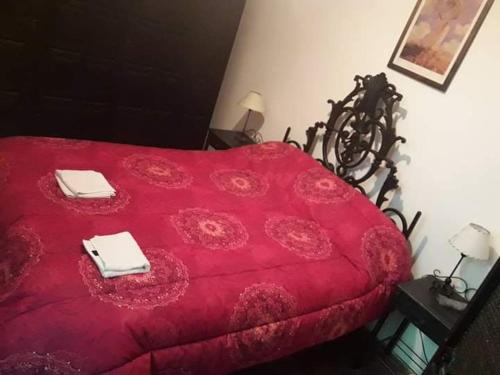 ein rotes Bett mit zwei Handtüchern darüber in der Unterkunft Casa de Oda in Salta