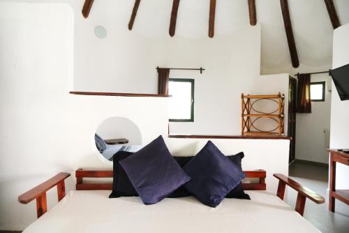 a bedroom with a white bed with purple pillows at Hotel Uolis Nah in Tulum