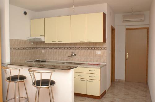 a kitchen with white cabinets and two bar stools at Apartments and rooms by the sea Milna, Hvar - 3074 in Hvar