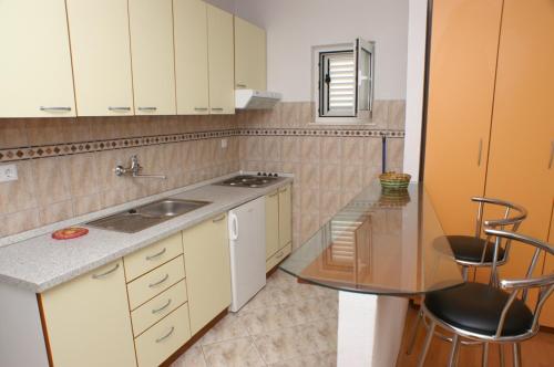 a kitchen with white cabinets and a sink and a table at Studio Milna 3074c in Hvar