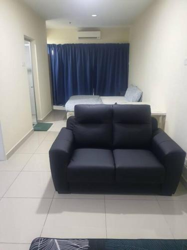 a living room with a black couch and a bed at Lovely studio condo with balcony & pool @ Suria Jelutong in Shah Alam