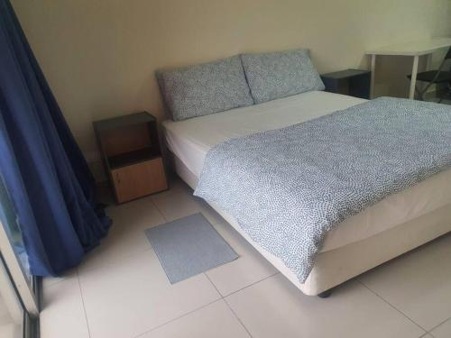 a bedroom with a bed with a blue comforter at Lovely studio condo with balcony & pool @ Suria Jelutong in Shah Alam