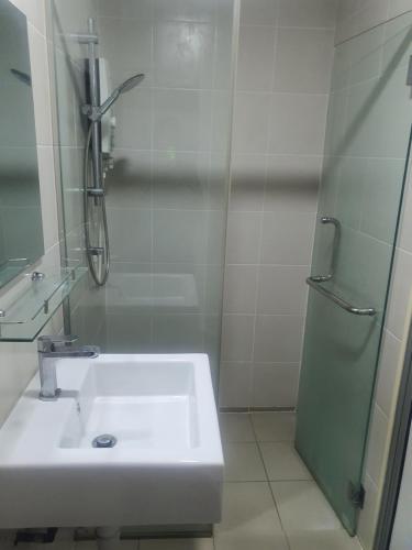 a white bathroom with a sink and a shower at Lovely studio condo with balcony & pool @ Suria Jelutong in Shah Alam