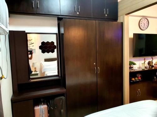 a bedroom with brown cabinets and a tv and a bed at Condominium Shore 1 Mall of Asia in Manila