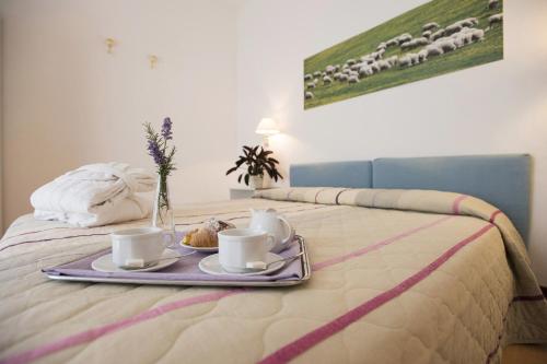 a tray with coffee cups and muffins on a bed at Hotel Angiolino in Chianciano Terme