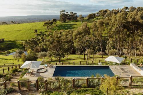 a pool with umbrellas and a hill in the background at TIMBA - Luxury bush retreat with pool, spa & gym in The Range