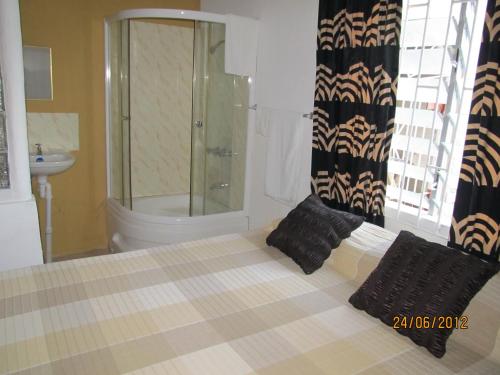 uma casa de banho com um chuveiro e uma cama com almofadas pretas em Barefoot Guest House em Belfast