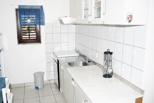 een witte keuken met een wastafel en een aanrecht bij Apartment Mandre 3084c in Kolan